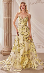 A woman poses indoors in the Lemon Yellow Floral-Print Long Prom Dress A0770, featuring a fitted bodice and flared train. The elegant floral formal dress flows gracefully as she stands near a column with draped white fabric.