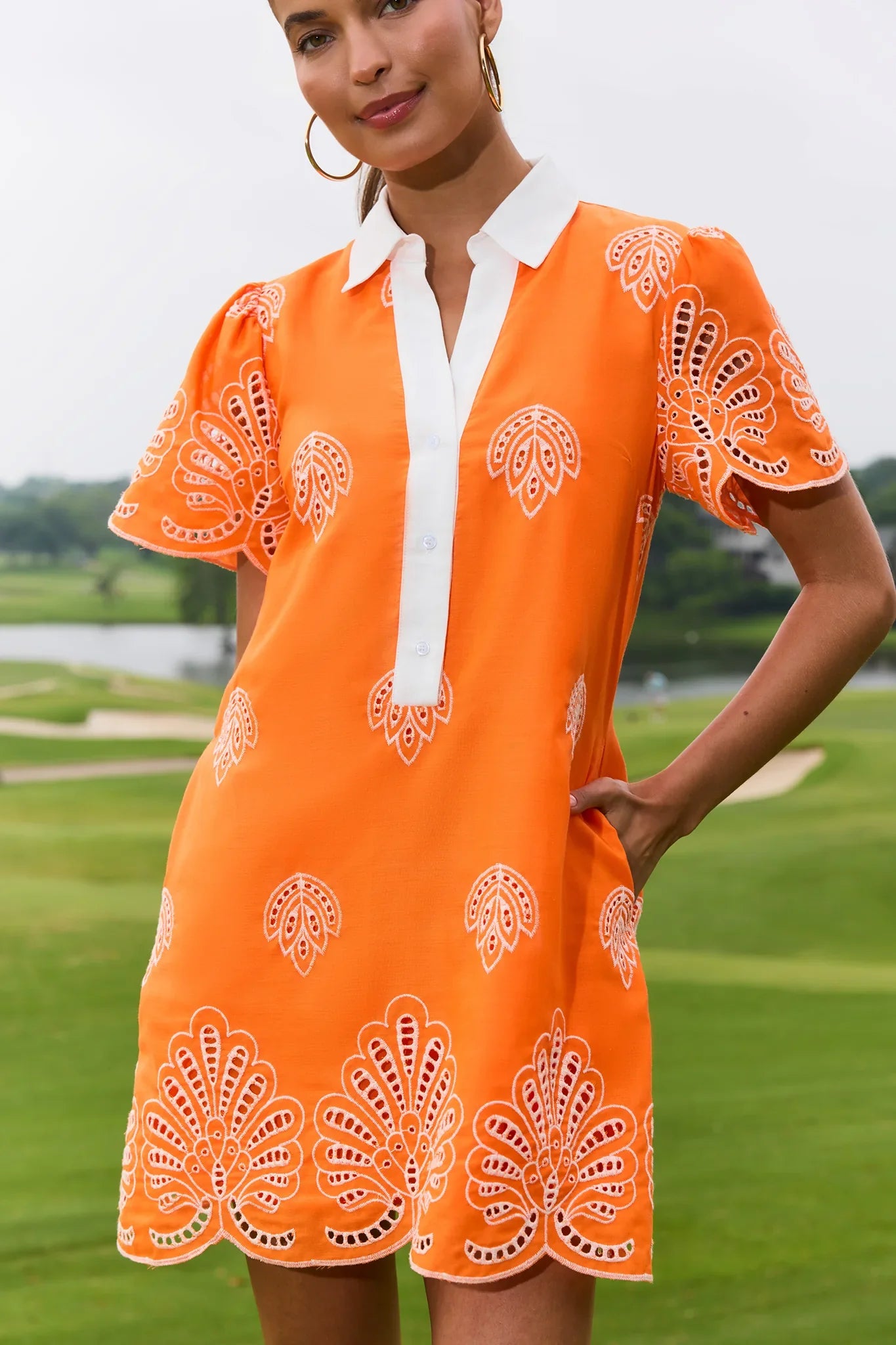 Woman wearing an orange dress with white patterns on a golf course