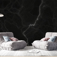 Black marble wallpaper with white veins creating a dramatic effect in a modern living room with high ceilings