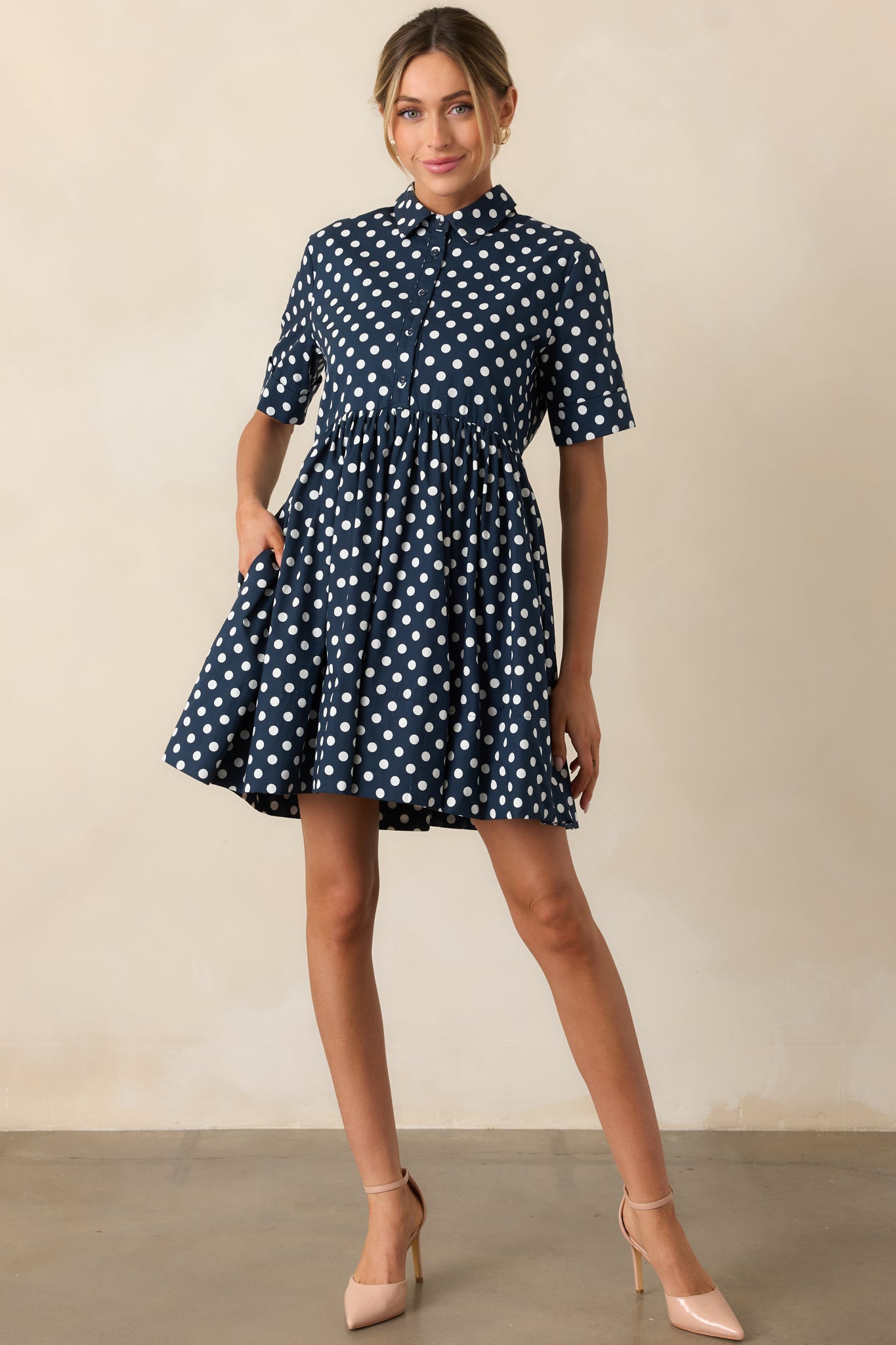 Front view of navy mini dress with white polka dots and collared neckline.