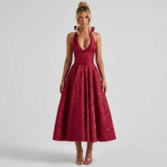 Front view of a woman wearing the Kouvr red floral jacquard halter neck midi dress featuring a structured corset bodice and deep plunging neckline.