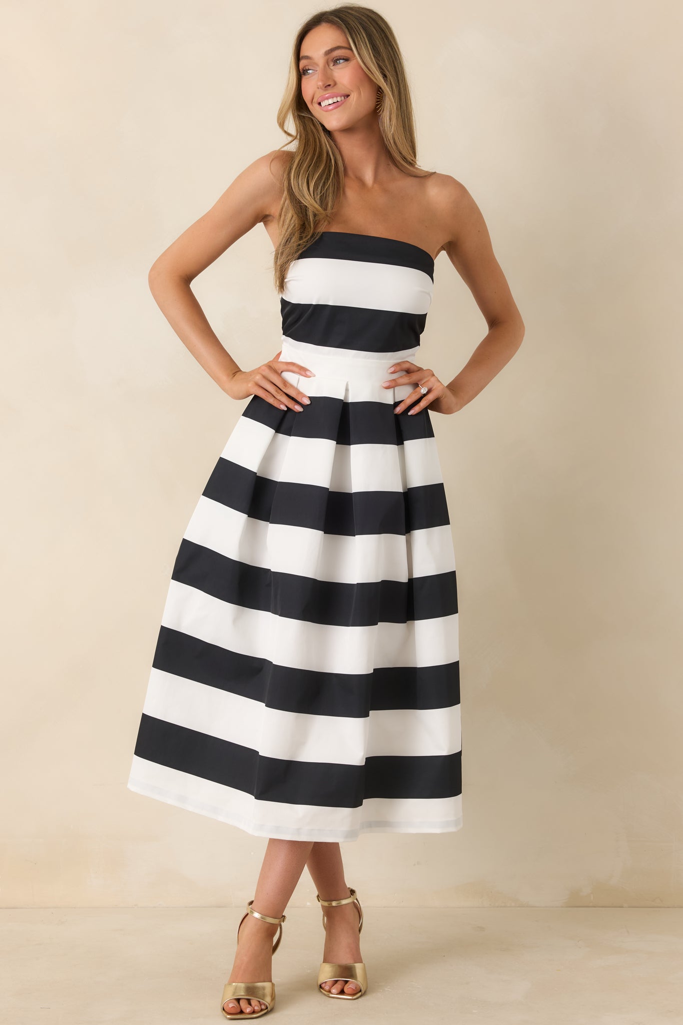 Woman wearing a black and white striped strapless dress against a beige background.