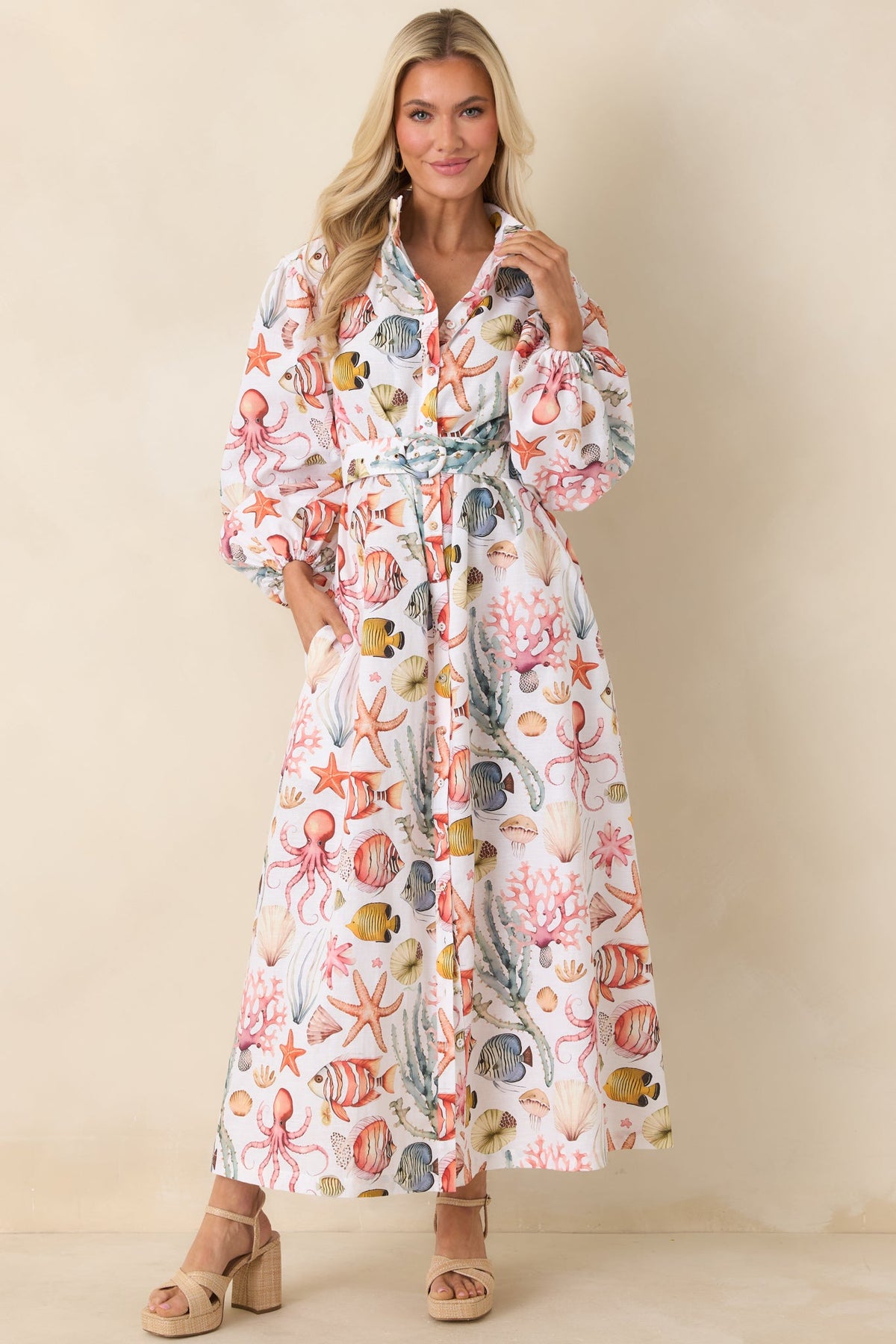 Maxi dress with collared neckline, full button-front closure, removable waist belt, and voluminous long sleeves with elastic cuffs.
