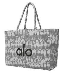Alo Yoga Mat Tote in Grey Tie-Dye design, featuring a spacious interior for yoga essentials. The tote is crafted for durability and style, perfect for carrying mats and accessories. Ideal for yoga enthusiasts seeking a fashionable and functional bag.