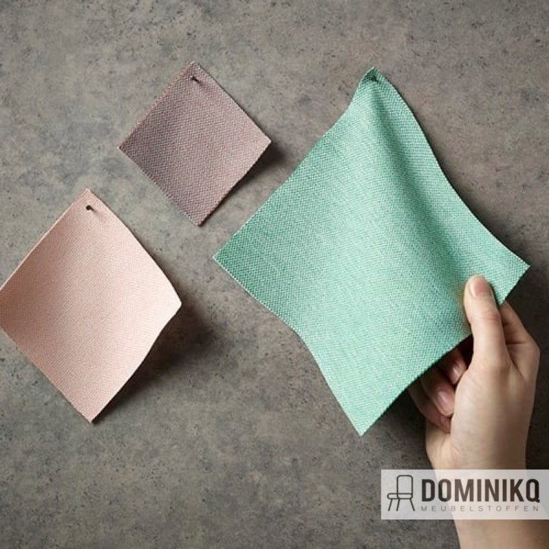 Hand houdt Camira Fabrics Era stoffenstaal in groen met visgraat structuur naast andere kleursamples op grijze achtergrond.