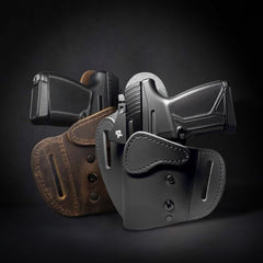 Three leather OWB (Outside-the-Waistband) holsters, two in black and one in brown, displayed with firearms inserted, against a dark background.