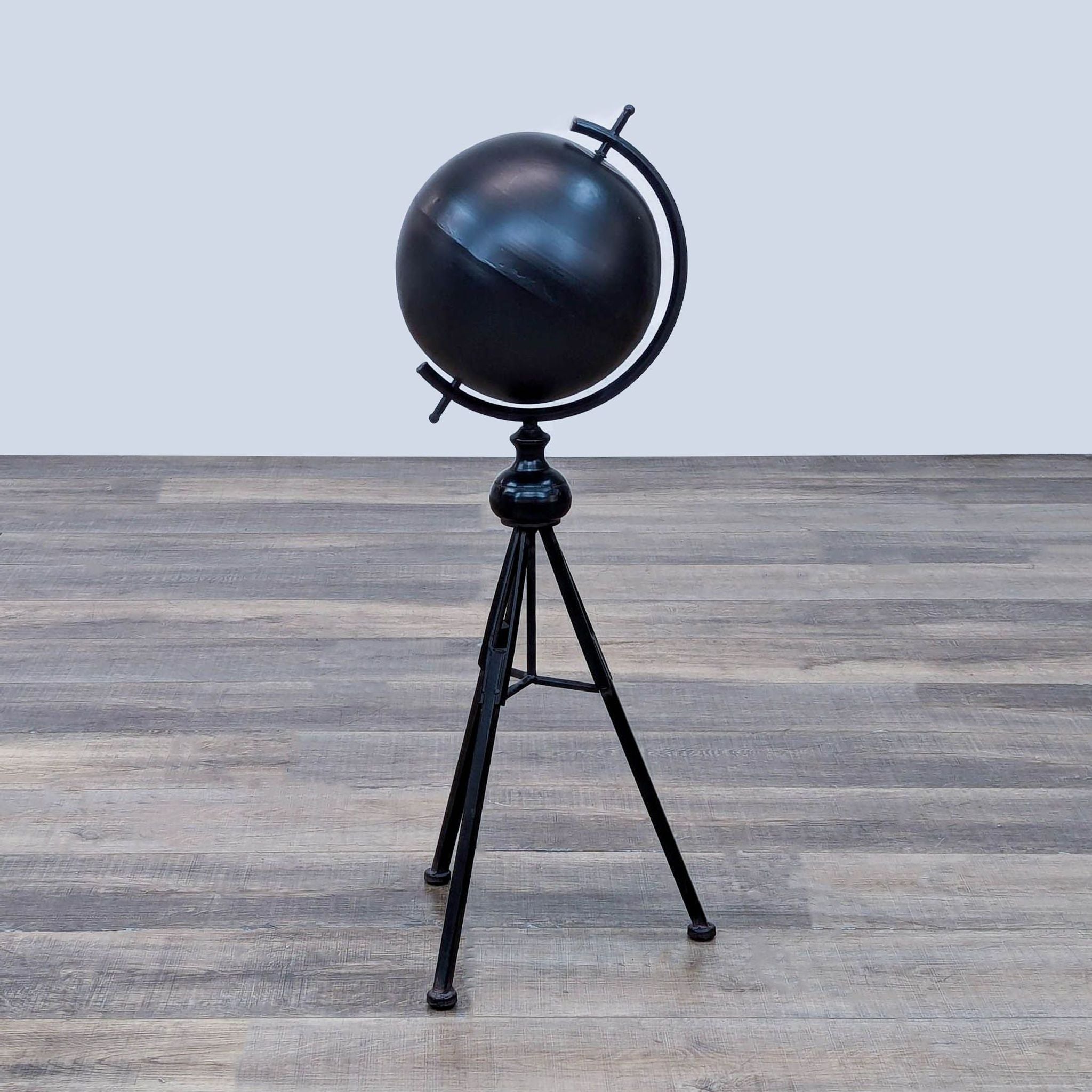 Black spherical globe on a tripod stand with a minimalist design.