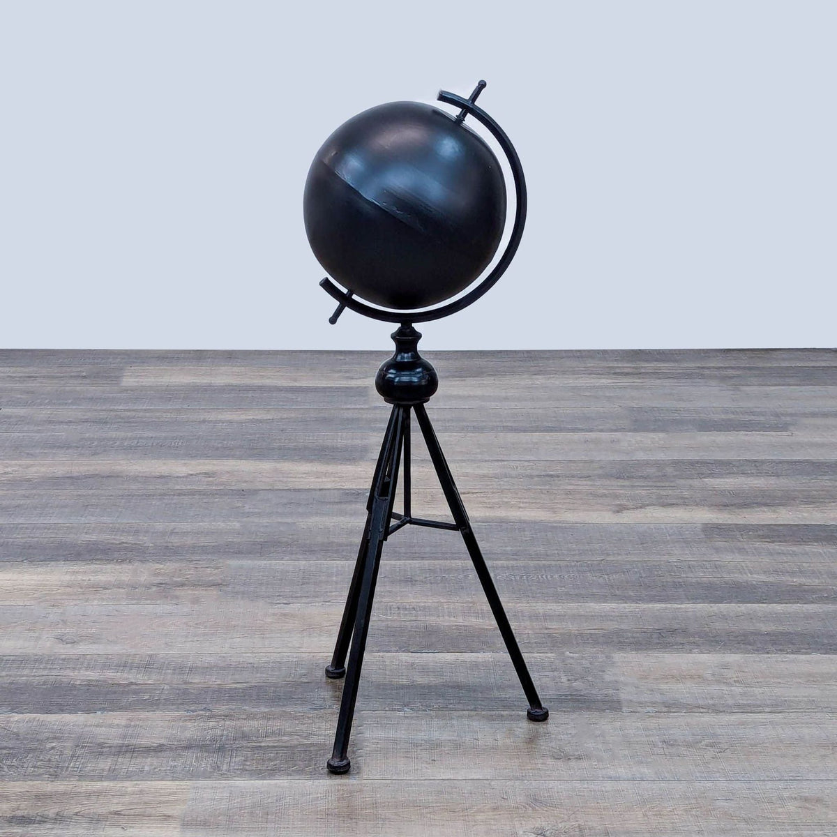 Black spherical globe on a tripod stand with a minimalist design.