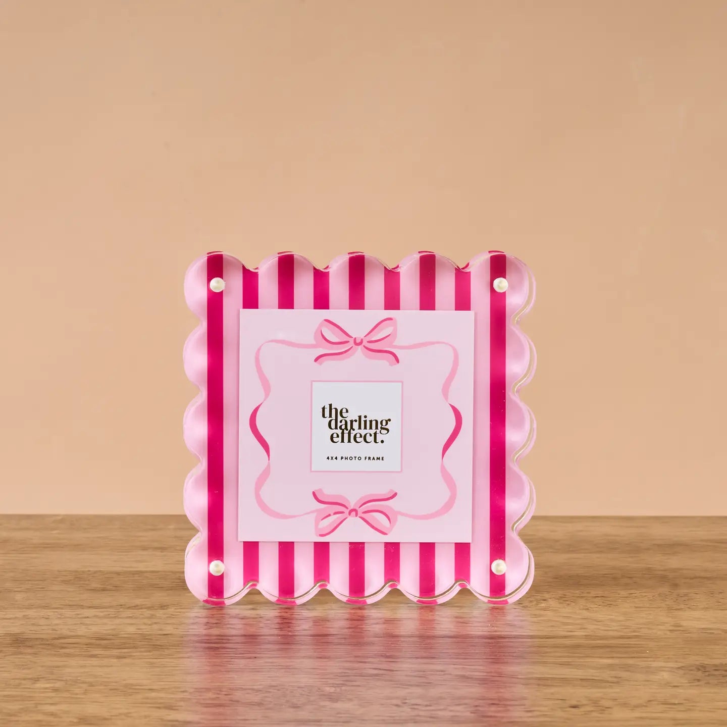 Pink and red striped photo frame on a wooden surface with  on a beige background