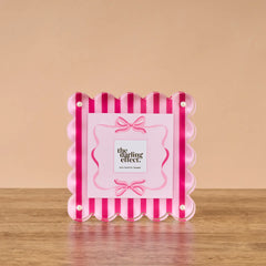Pink and red striped photo frame on a wooden surface with  on a beige background