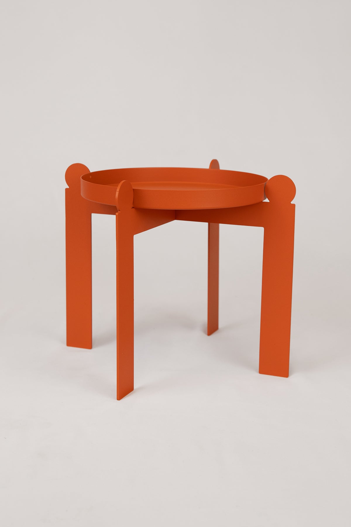 The Palla Multipurpose Plant Stand from Upton is a decorative steel plant stand or fruit bowl with a modern design. Shown here in the burnt orange color, on a white background.