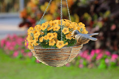 hanging plant basket shaped like nest with two sparrow perched - shown with petunias in a flower garden